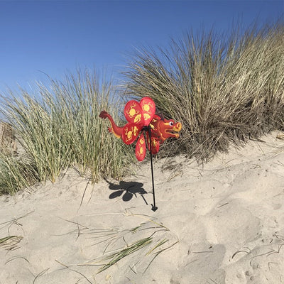 Alt text: "12-inch Dragon Spinner with vibrant red dragon and flying petal design, elegantly displayed in a garden setting.