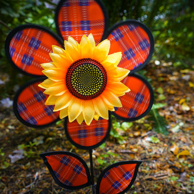 Alt text: "12-inch Red Plaid Flower with Leaves garden spinner featuring vibrant plaid petals and detailed sunflower center, displayed outdoors.