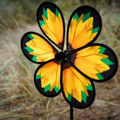 Alt Text: 13.5" sunflower spinner with six petals and green leaves displayed in a garden, twisting gently in the breeze on a fiberglass pole.