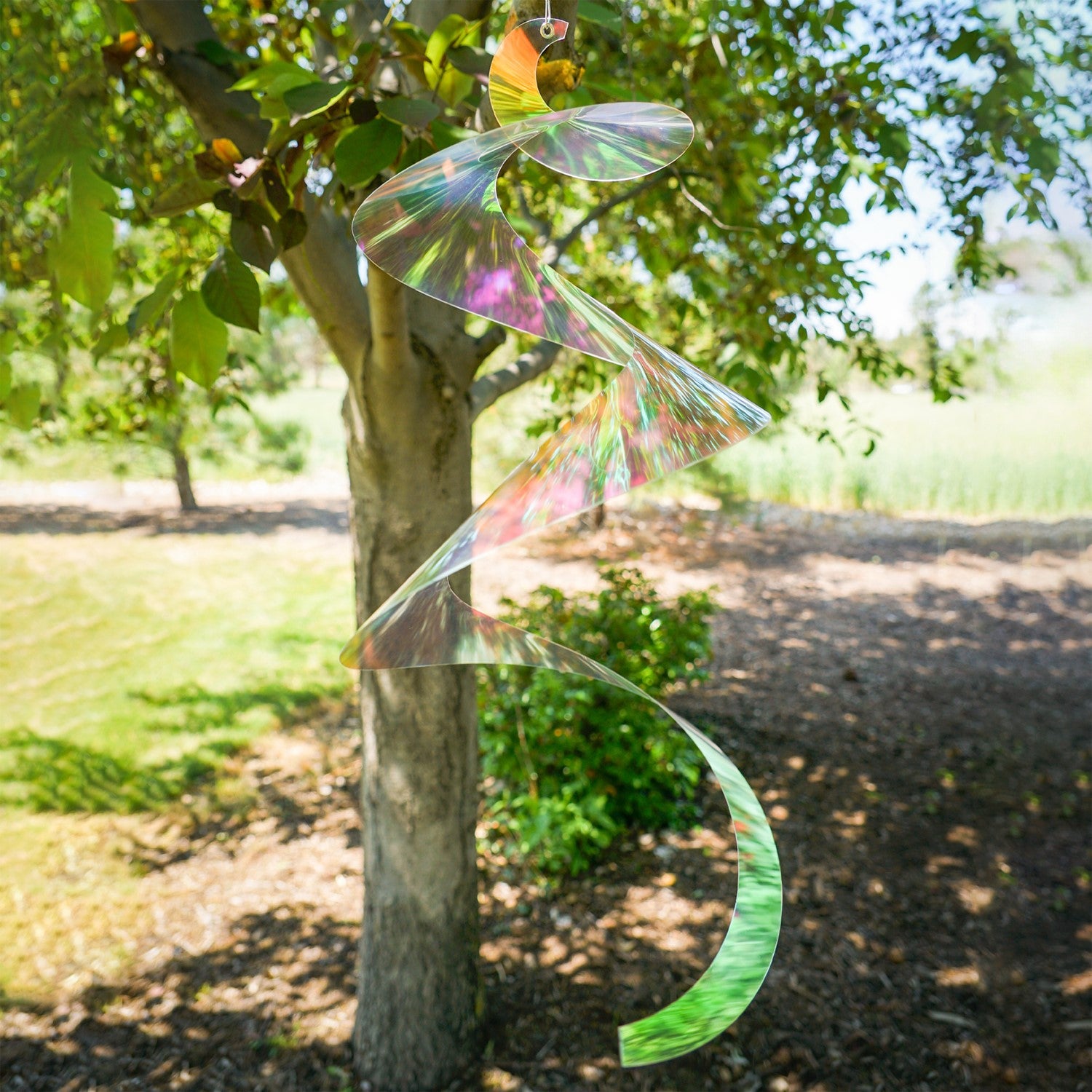 Alt Text: "30-inch iridescent twister tail made of Mylar, spinning gracefully in the sunlight, showcasing vibrant colors and reflections in an outdoor setting.
