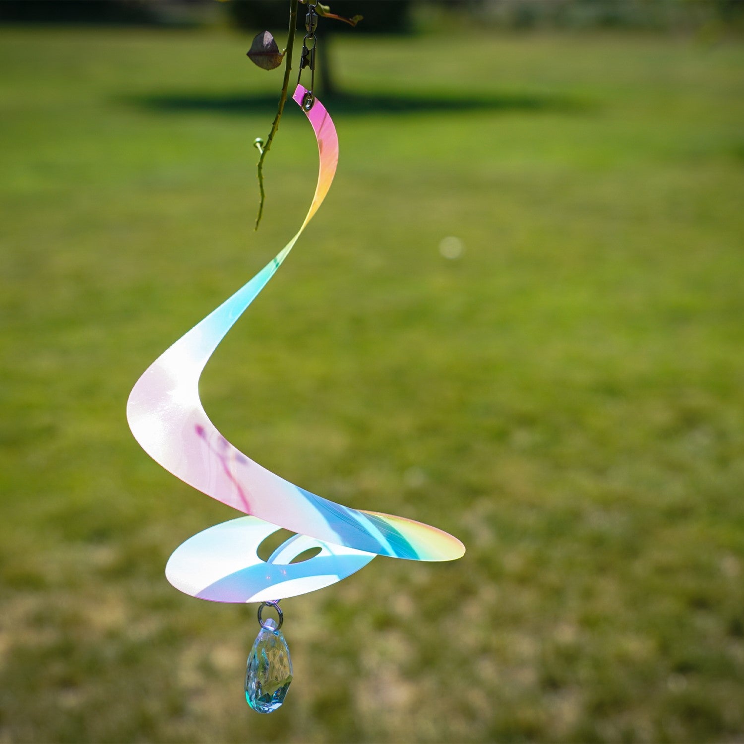 Alt Text: 8" Striped Iridescent Tear Drop Curlie with attached crystal spinner, displaying vibrant colors while hanging outdoors in a sunshine-filled garden.
