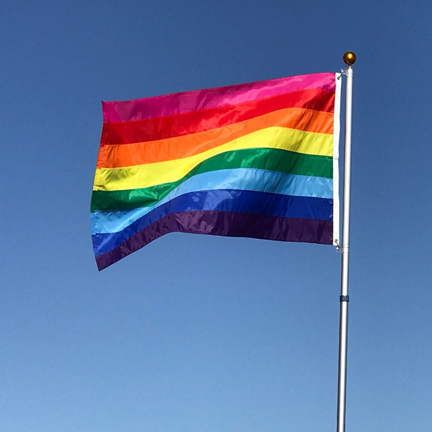 **Alt Text** Historic Pride 3x5 Grommet Flag displaying Gilbert Baker's eight-stripe design outdoors, symbolizing LGBTQ+ pride and diversity.