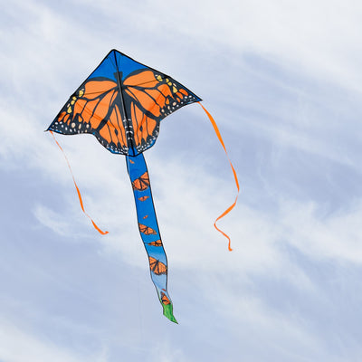 Alt text: "Monarch Swarm 45-inch Fly-Hi Kite soaring through a clear blue sky with colorful butterfly design and streamer tails.