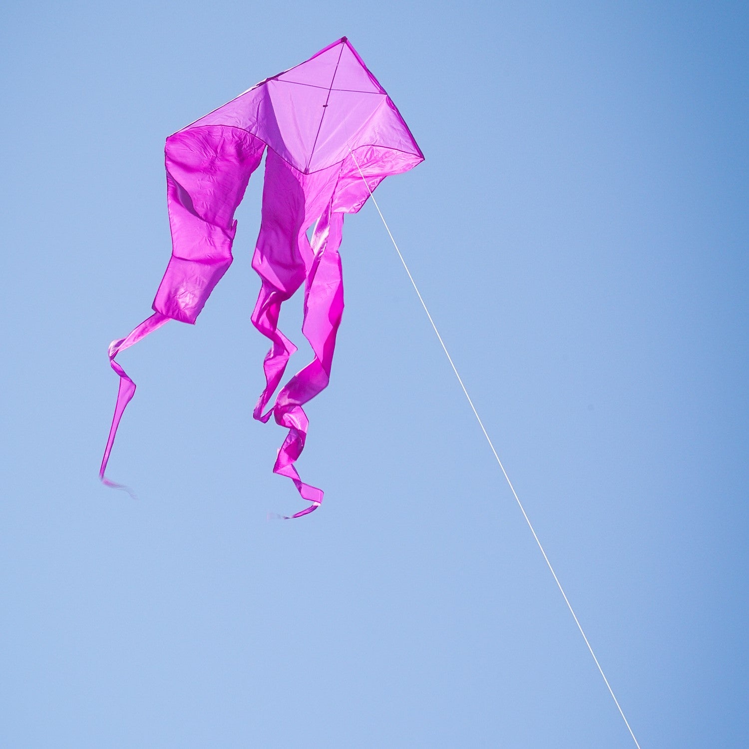 Alt Text: Purple 52" Wave Delta Kite soaring high in the sky, showcasing flowing tails and a vibrant color against a clear background.