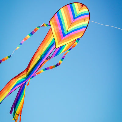 Alt text: "22-inch Rainbow Stripe Dancing Dragon Kite, featuring colorful tails and ripstop fabric, soaring in a sunny sky.