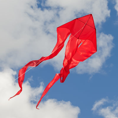 Alt Text: "Red 52-inch Wave Delta Kite soaring in a bright blue sky with long flowing tails, showcasing an elegant design perfect for outdoor fun.