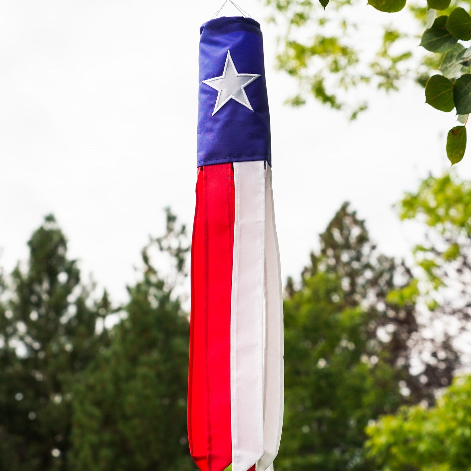 **Alt Text:** "Texas 18-inch windsock displaying the Texas flag and star, fluttering in the breeze with vibrant color-coordinated tails.