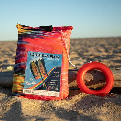 Alt Text: 7.5 Tie Dye Black Air Foil Kite flying against a clear blue sky, showcasing its vivid tie dye pattern and colorful tails in motion.