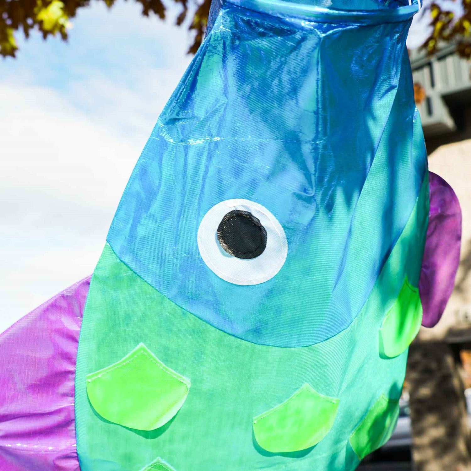 48-inch Iridescent Cool Damsel Fish Windsock displaying shimmering scales in a garden setting, showcasing its unique colors under sunlight.