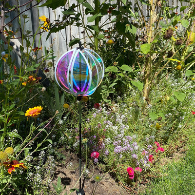 Iridescent 8.5-inch Gazing Ball Spinner reflecting sunlight, showcasing its vibrant colors in a beautifully landscaped garden.