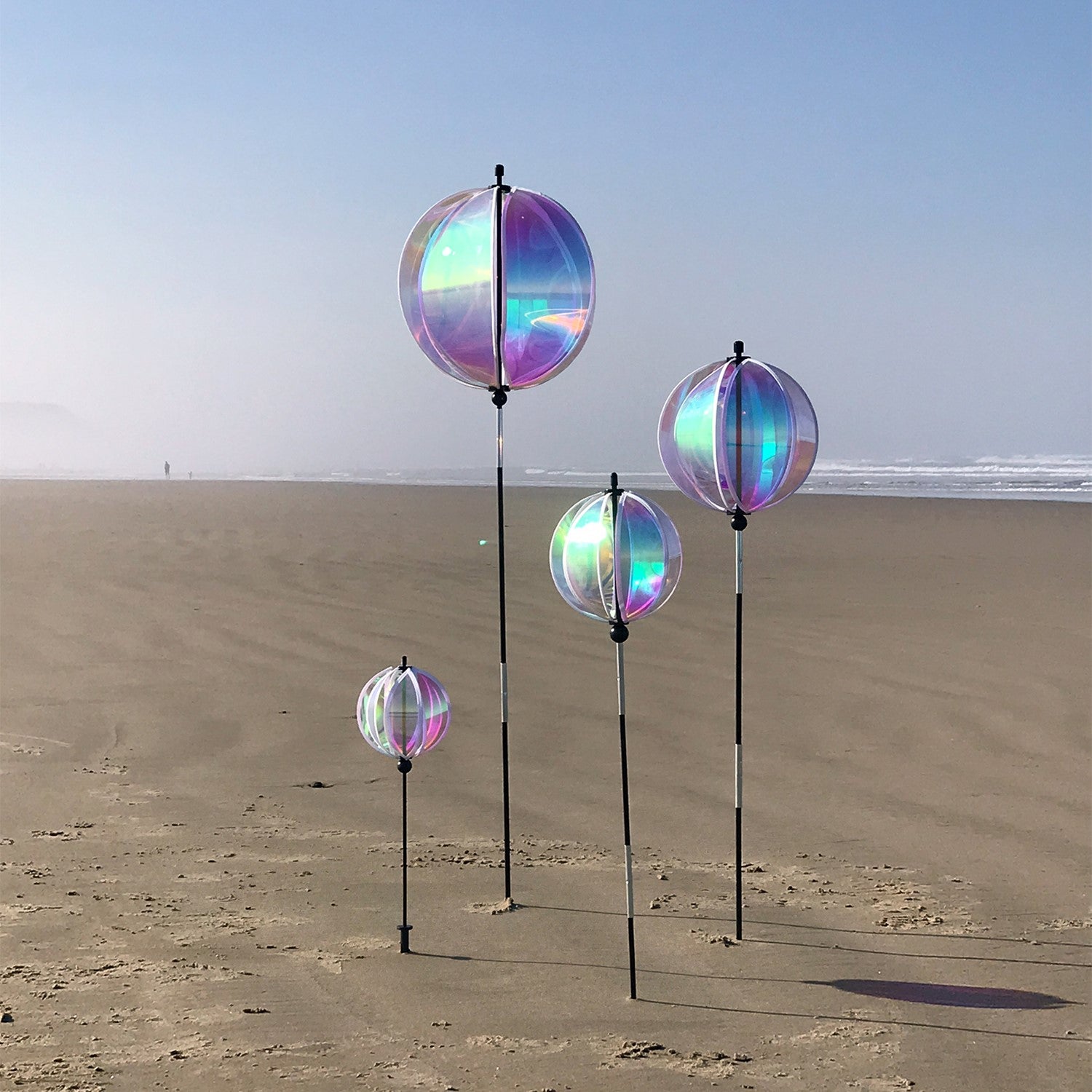Iridescent 8.5-inch Gazing Ball Spinner reflecting sunlight, showcasing its vibrant colors in a beautifully landscaped garden.