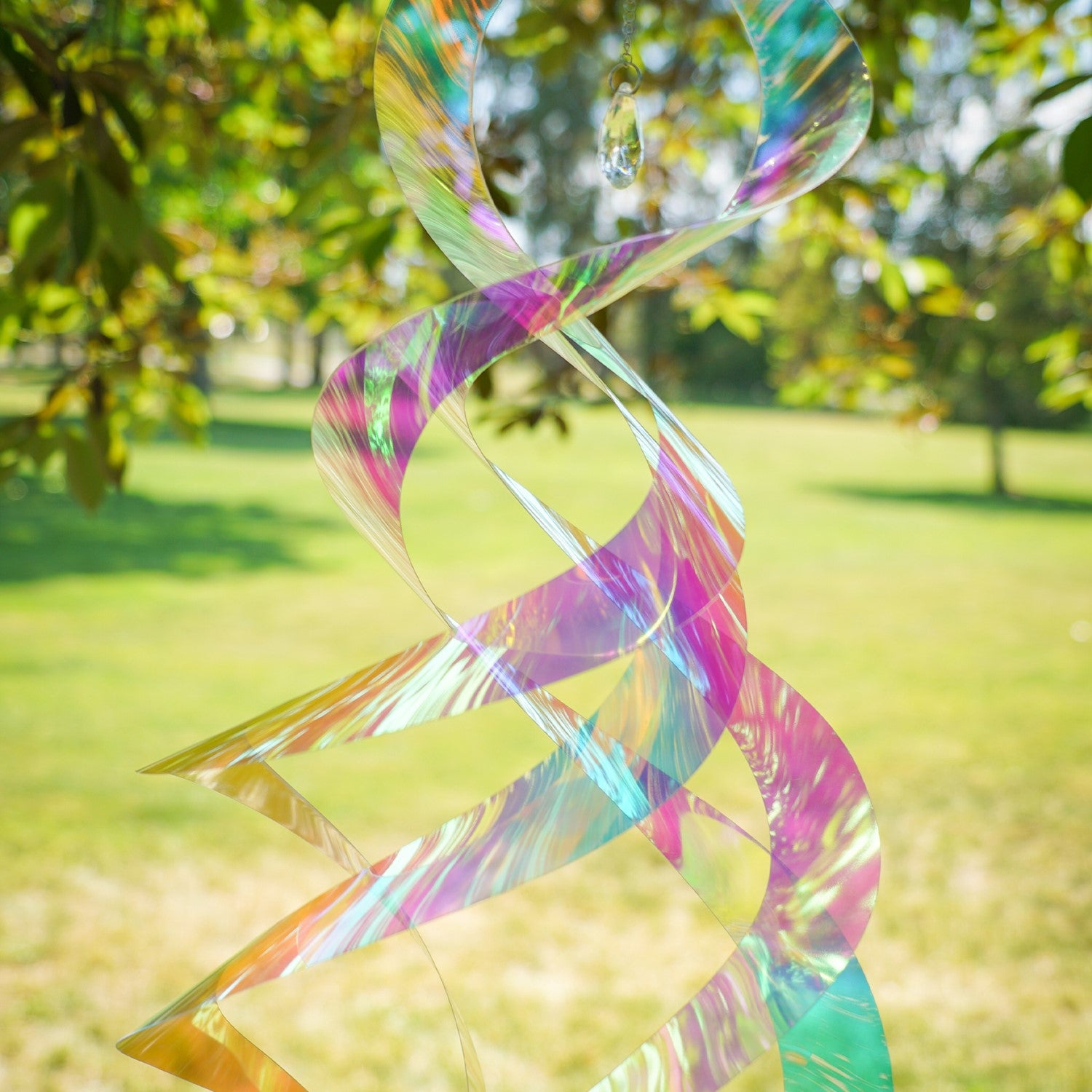 Iridescent Mylar Spin Quartet with Crystal spinning gracefully on a garden hook against a bright blue sky, showcasing vibrant colors and sparkles.