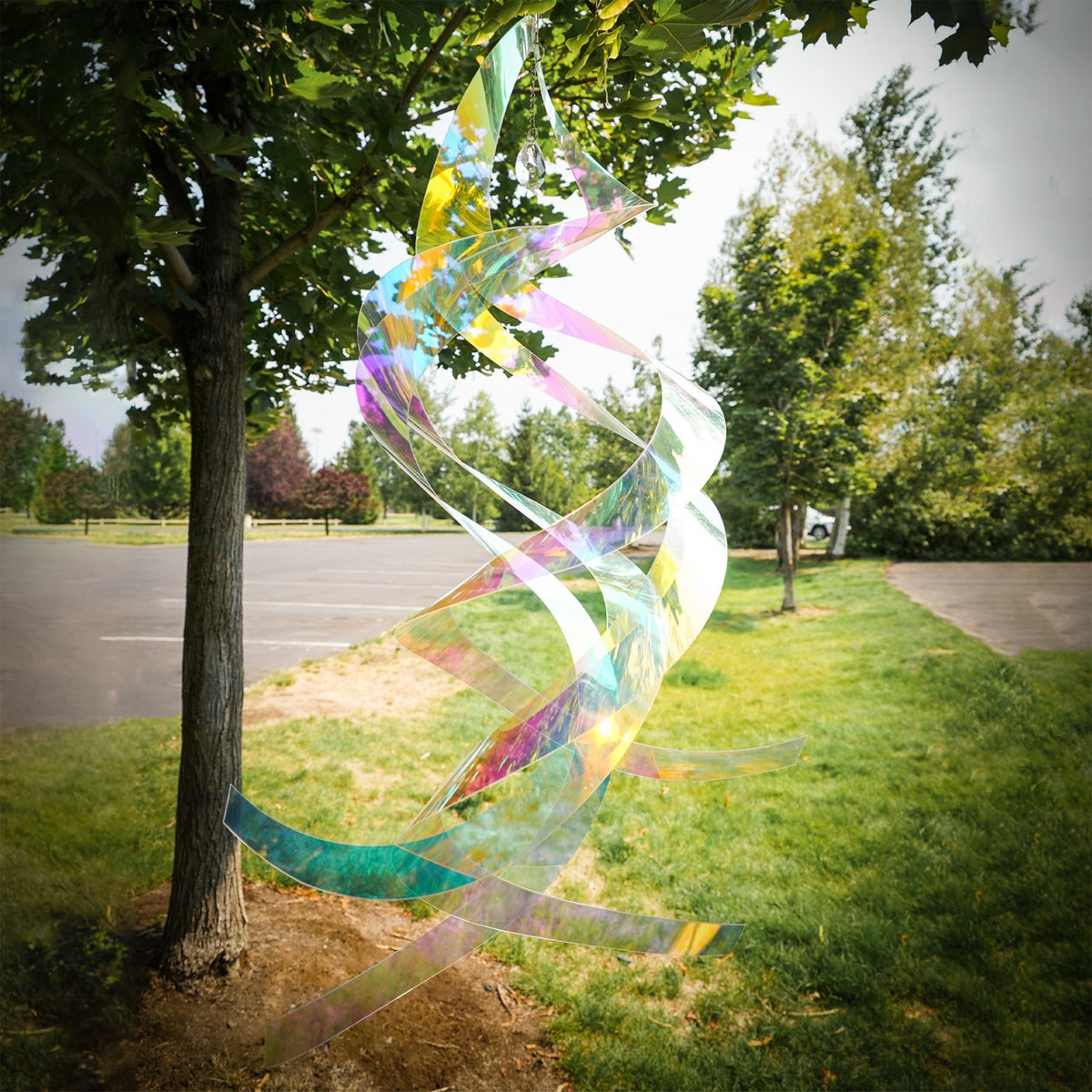 Iridescent Mylar Spin Quartet with Crystal spinning gracefully on a garden hook against a bright blue sky, showcasing vibrant colors and sparkles.