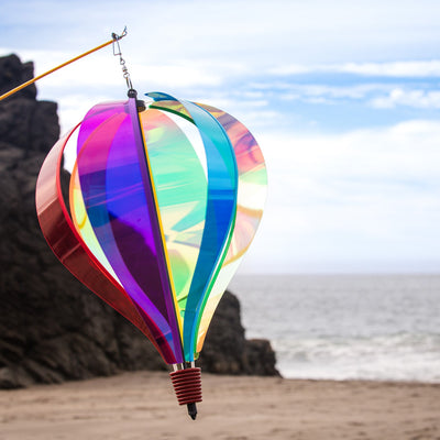 Iridescent Rainbow 6-Panel Hot Air Balloon spinner in vibrant colors, gently rotating in an outdoor garden setting.