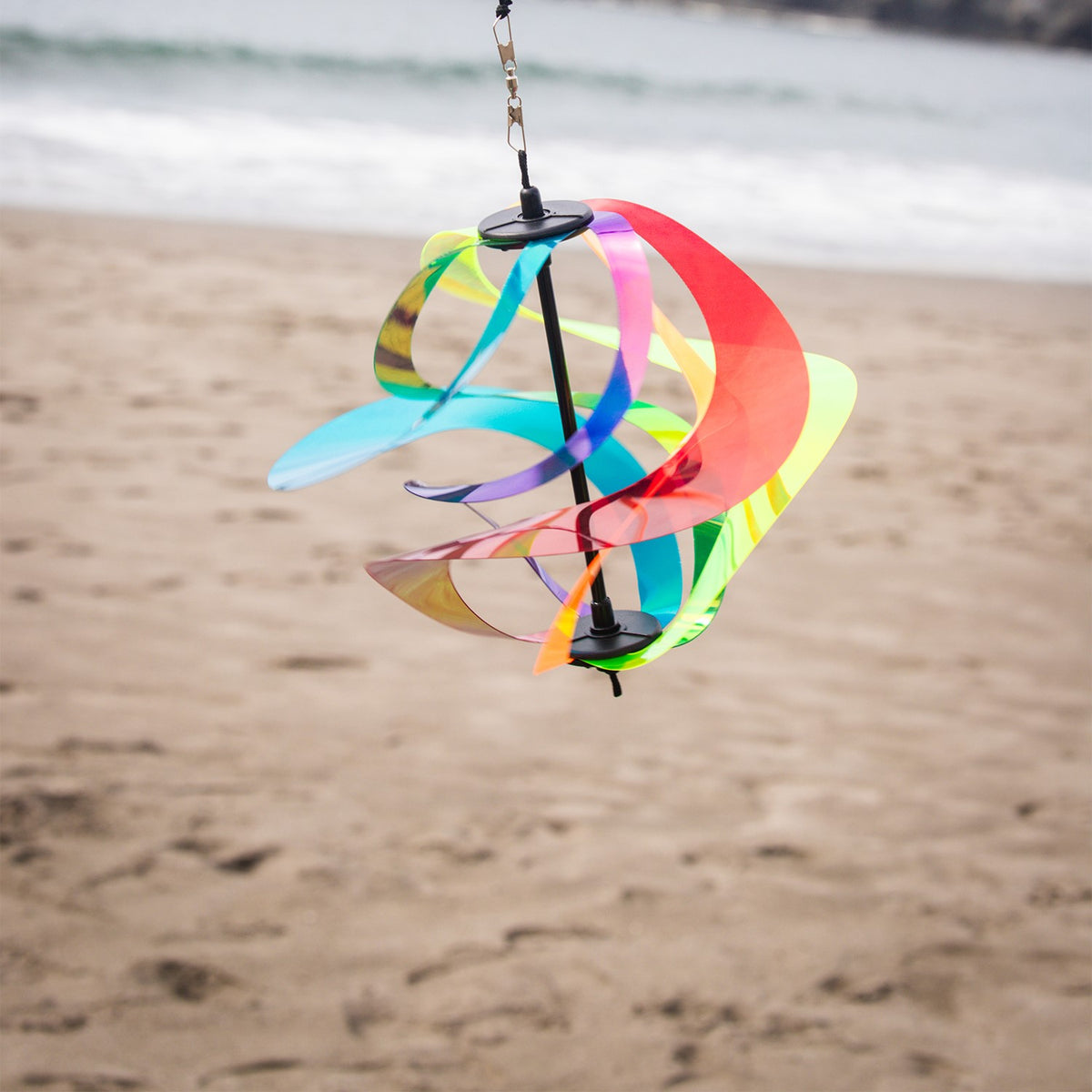 Iridescent Rainbow Vortex Spinner featuring six Mylar spirals hanging in a garden, shimmering in the breeze and reflecting light.