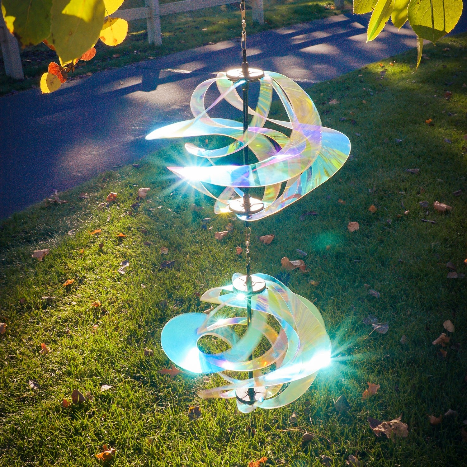 Iridescent Vortex Double Spinner showcasing interconnected Mylar spirals spinning in a sunny garden setting, creating a vibrant visual display.