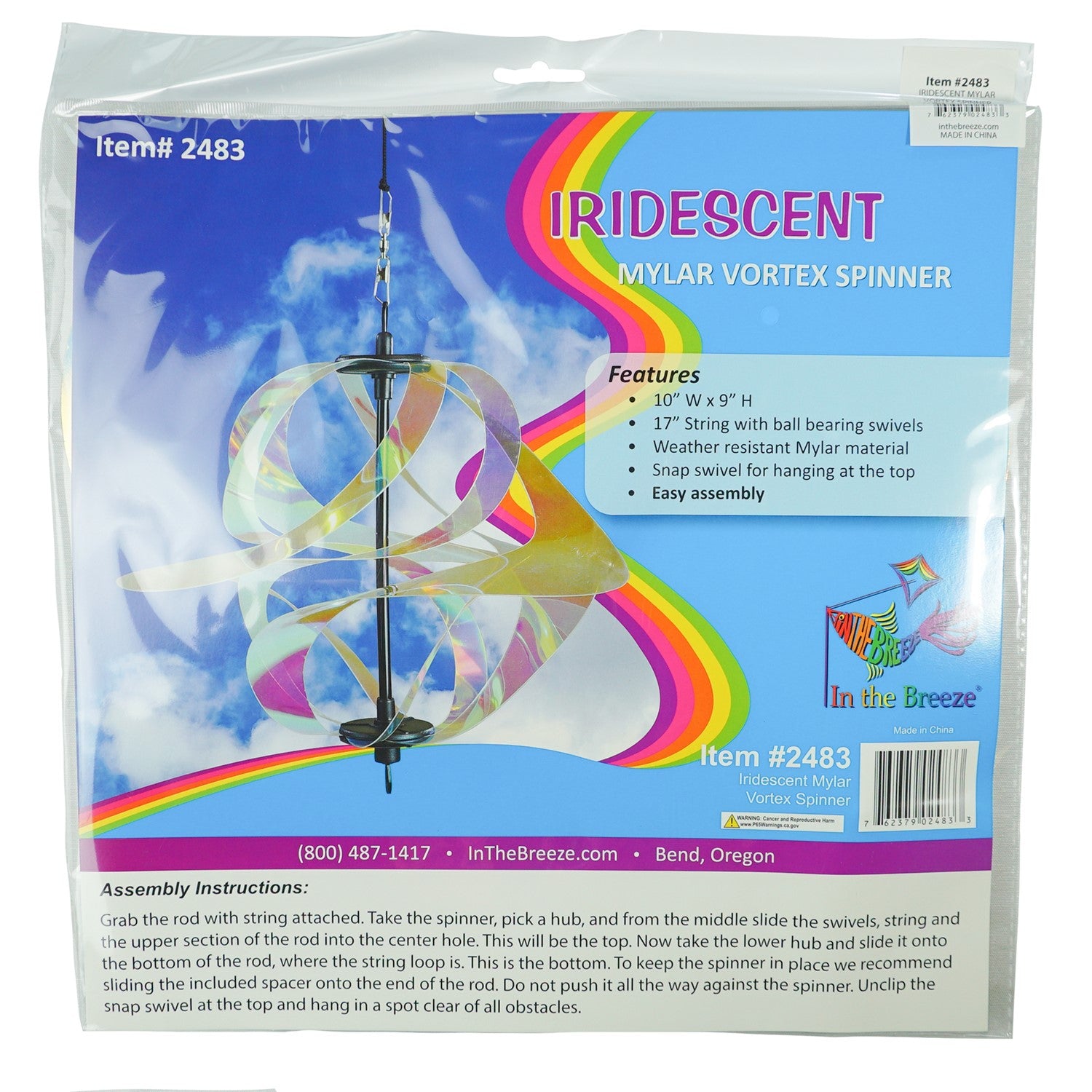 Iridescent Vortex Spinner with Mylar spirals suspended outdoors, reflecting sunlight in vibrant colors within a garden setting.