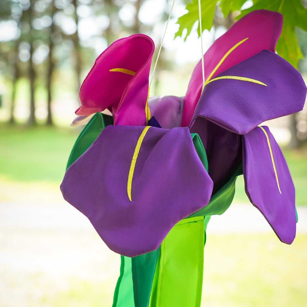 Iris Windtail features vibrant 3D iris flowers with colorful tails, gracefully hanging outdoors and rustling in the wind.