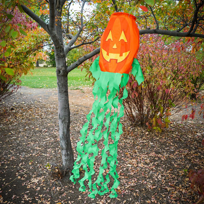 Jack O' Lantern 3D windsock featuring a vibrant pumpkin design and curlie streamer tails, displayed outdoors, fluttering in the breeze.