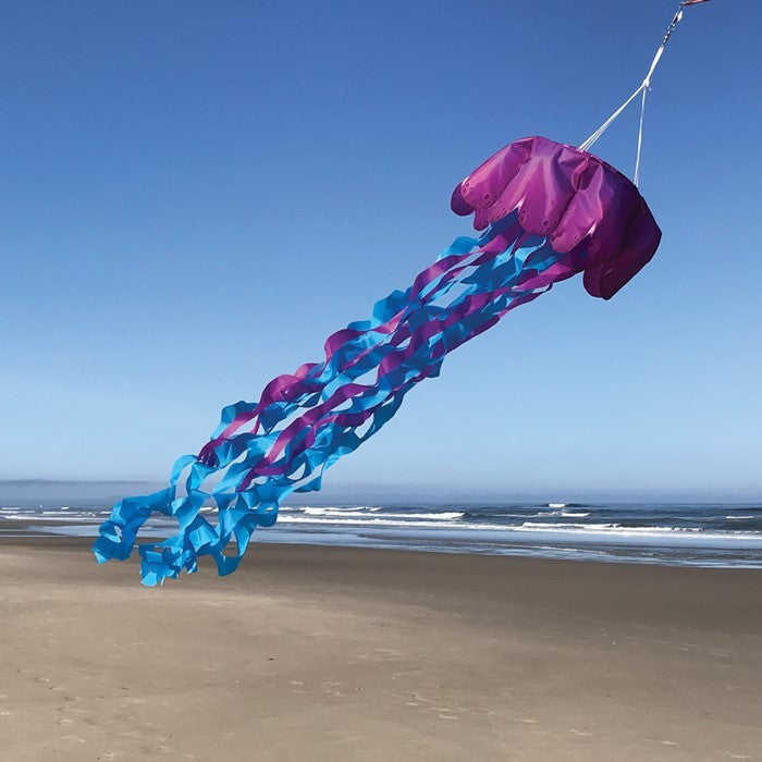 Jellyfish 3D Windsock in purple and blue colors hanging outdoors, showcasing vibrant tentacles fluttering in the wind against a bright sky.