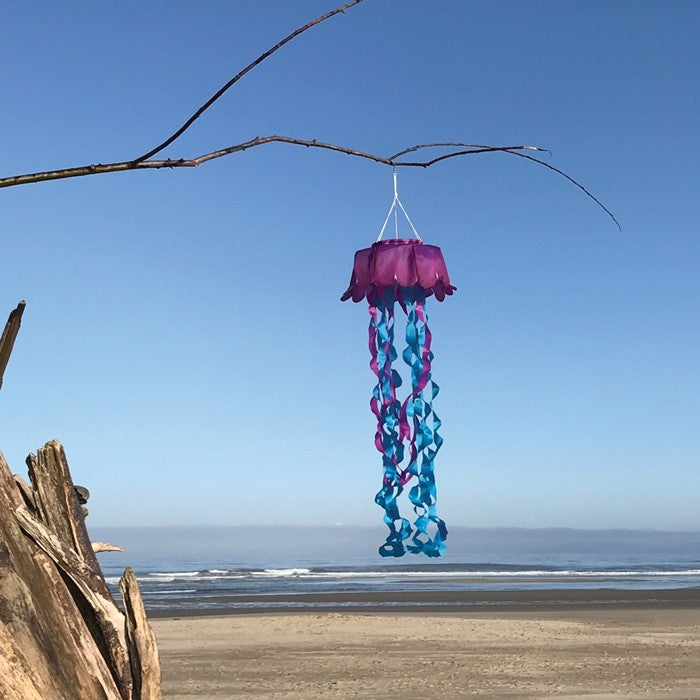 Jellyfish 3D Windsock in purple and blue colors hanging outdoors, showcasing vibrant tentacles fluttering in the wind against a bright sky.