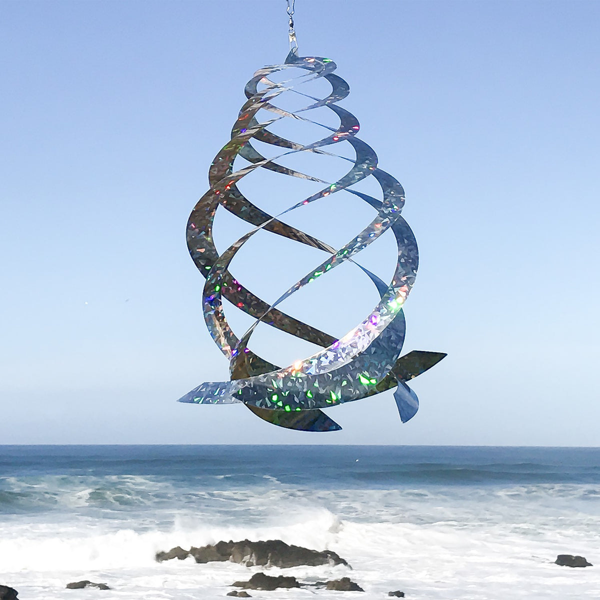 The Jewel Crystal Spinner displaying five reflective blades glimmering in sunlight, creating a spectrum of colors as it spins in a gentle breeze.