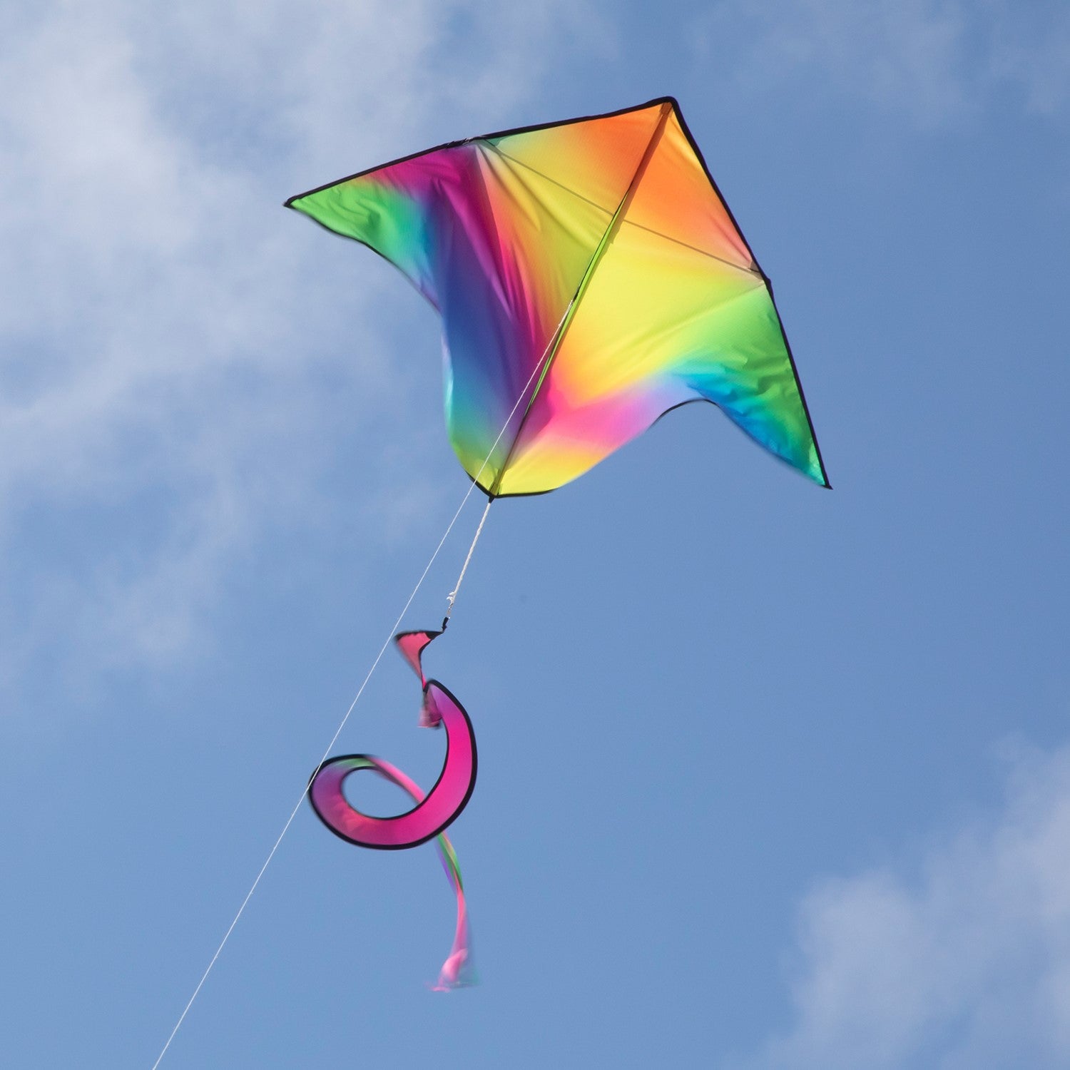 Jewel Delta with Spinning Tail kite featuring vibrant tie dye design in the sky during a sunny day, showcasing a fun outdoor activity.