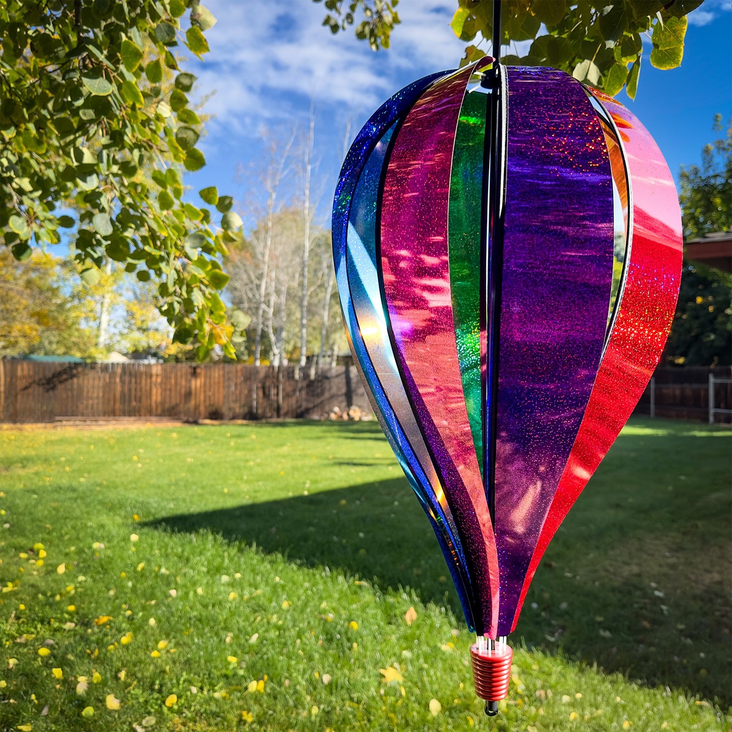 Jumbo Rainbow Glitter 8-Panel Hot Air Balloon spinning in outdoor garden, showcasing vibrant Mylar panels in rainbow colors.