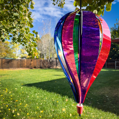 Jumbo Rainbow Glitter 8-Panel Hot Air Balloon spinning in outdoor garden, showcasing vibrant Mylar panels in rainbow colors.