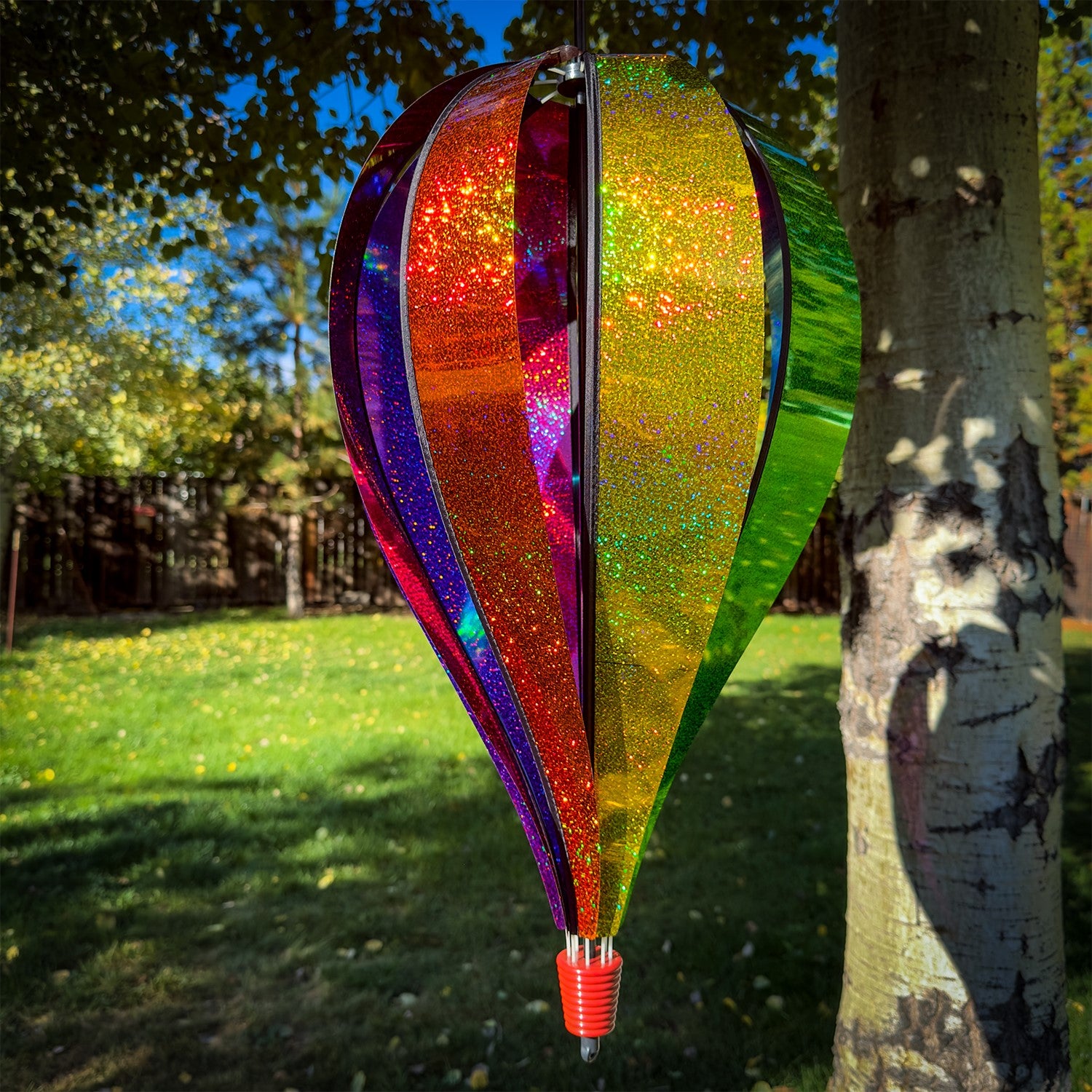 Jumbo Rainbow Glitter 8-Panel Hot Air Balloon spinning in outdoor garden, showcasing vibrant Mylar panels in rainbow colors.