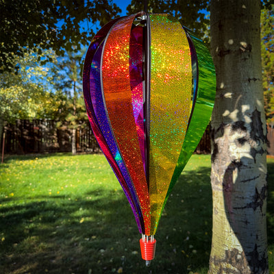Jumbo Rainbow Glitter 8-Panel Hot Air Balloon spinning in outdoor garden, showcasing vibrant Mylar panels in rainbow colors.