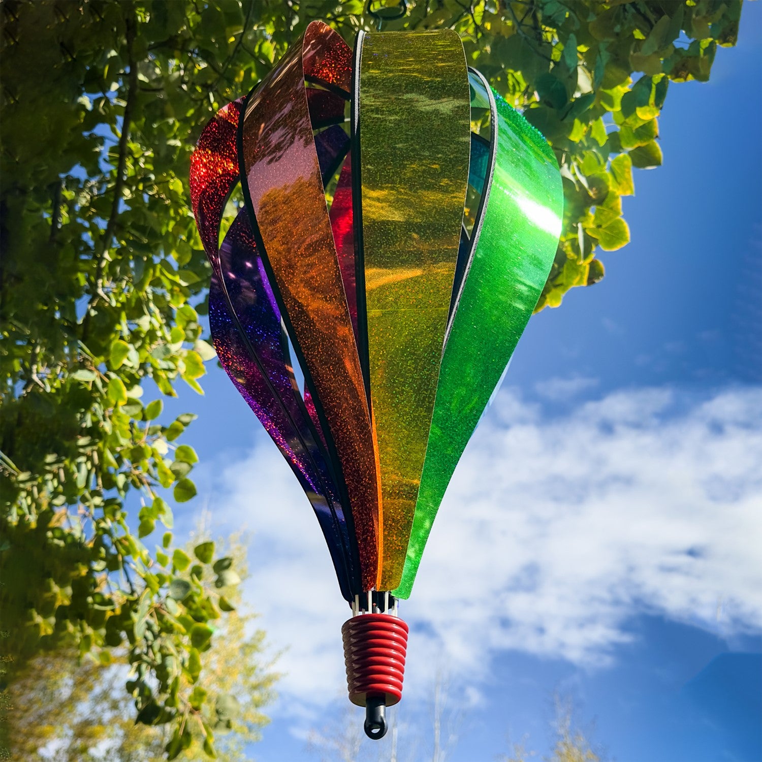 Jumbo Rainbow Glitter 8-Panel Hot Air Balloon spinning in outdoor garden, showcasing vibrant Mylar panels in rainbow colors.