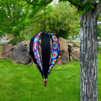 Jumbo Tie Dye 8-Panel Hot Air Balloon spinning in a garden, showcasing its colorful tie-dye design against a clear blue sky.
