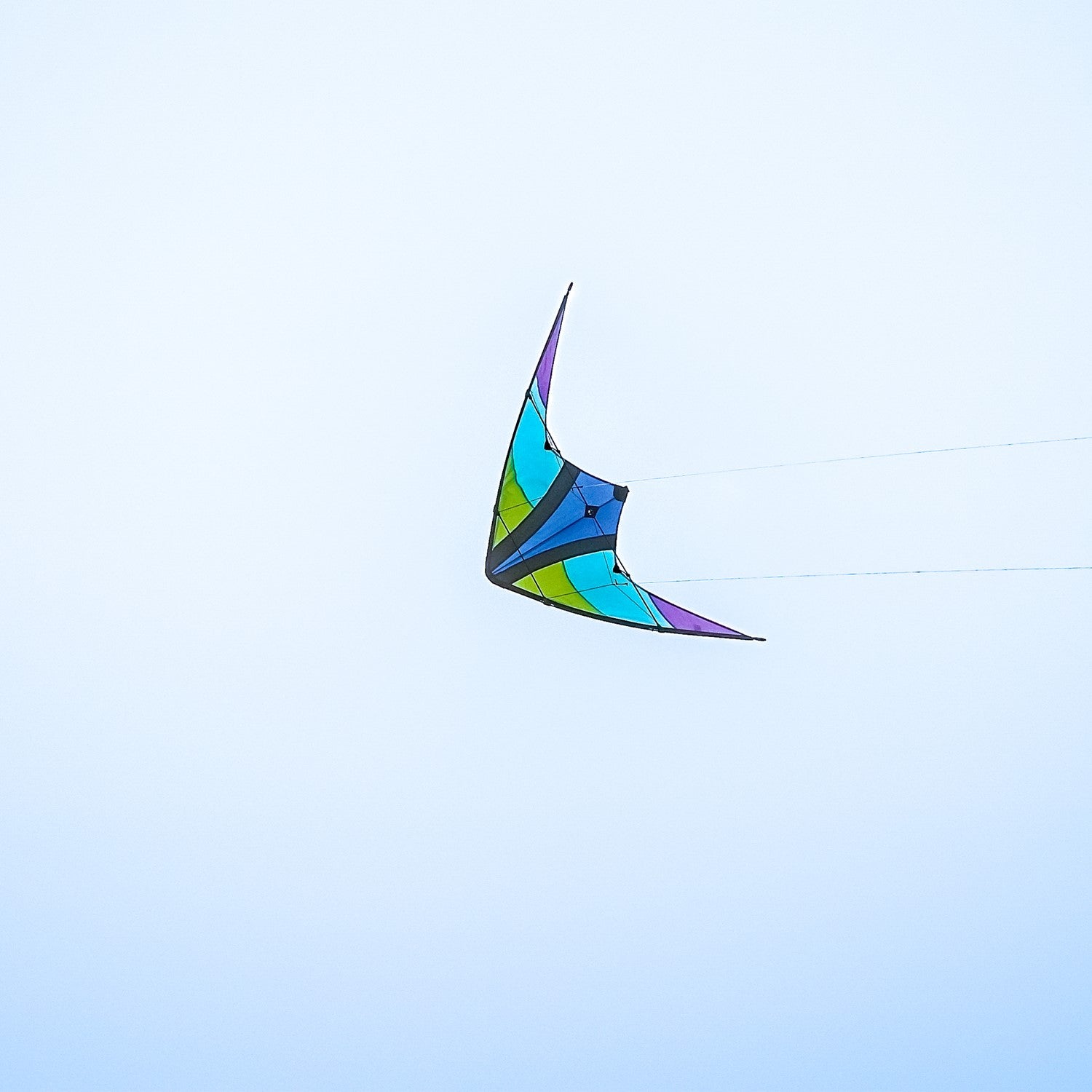 Kai 63' Sport Kite soaring against a bright blue sky, featuring vivid colors and a sleek two-line design ideal for outdoor enthusiasts.