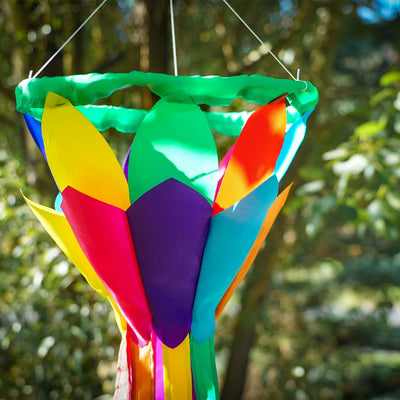 Kaleidoscope 38-inch Lotus Flower Windsock featuring bright petals and flowing rainbow tails, displayed outdoors in a garden setting.