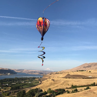Visualize a colorful Kokopelli Hot Air Balloon spinner measuring 26 inches, elegantly spinning in the breeze, showcasing vibrant Southwest-themed designs against a clear sky.