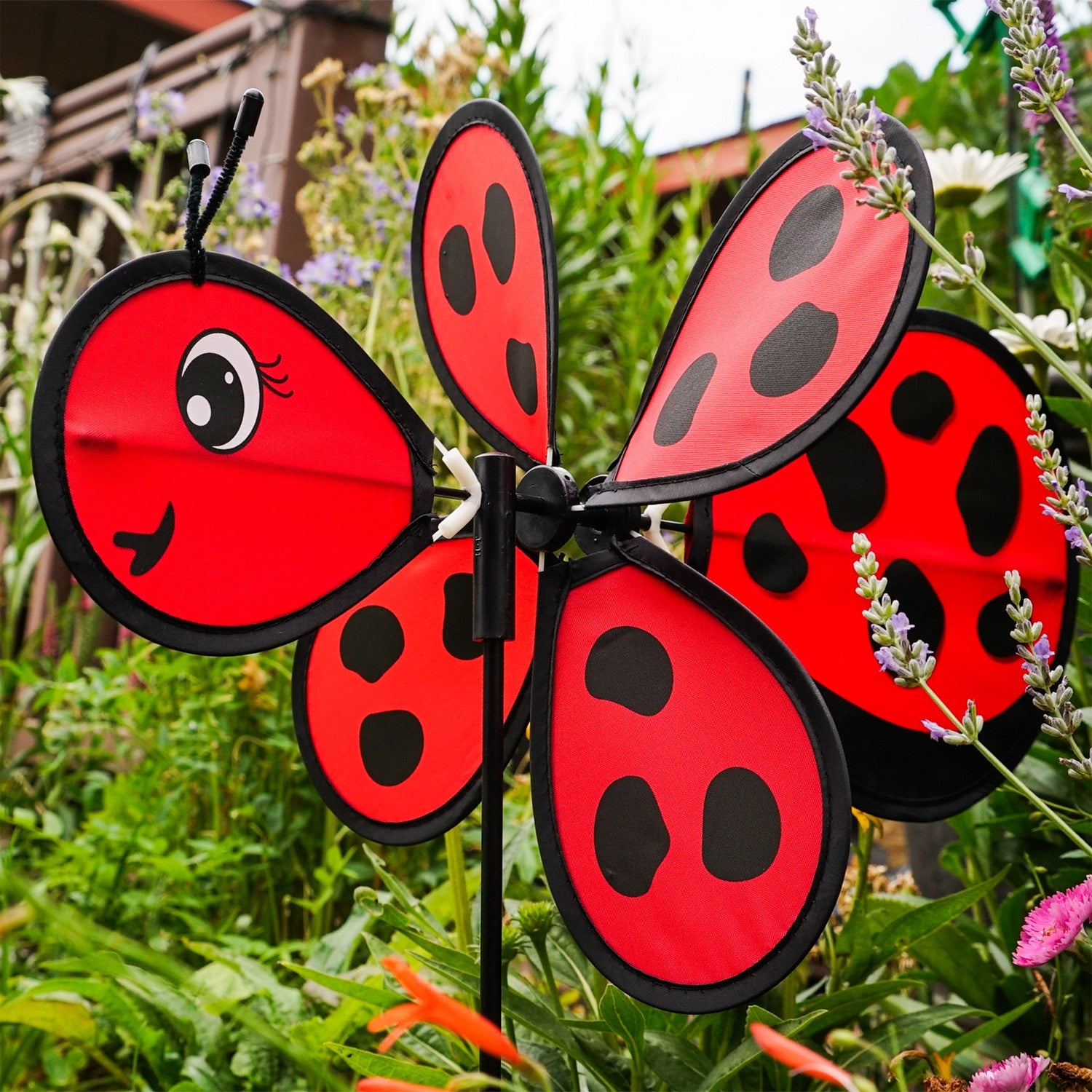 Ladybug Baby Spinner featuring a colorful 12-inch wheel on a sturdy fiberglass pole, designed for lively outdoor decoration in a garden setting.