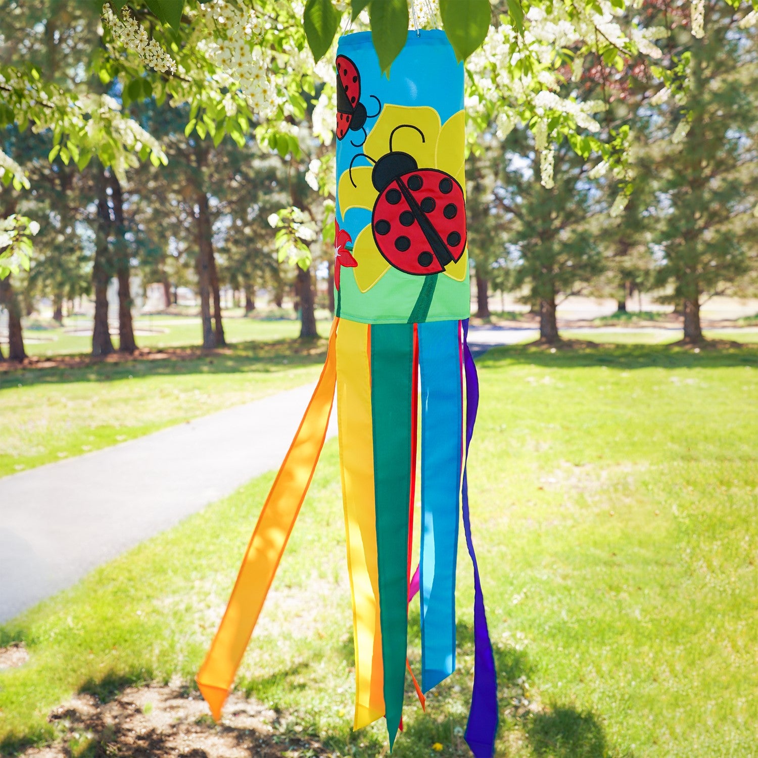 A stunning Ladybug Flower 40" windsock featuring vibrant colors and detailed appliqued graphics, fluttering gracefully with eight coordinating tails.