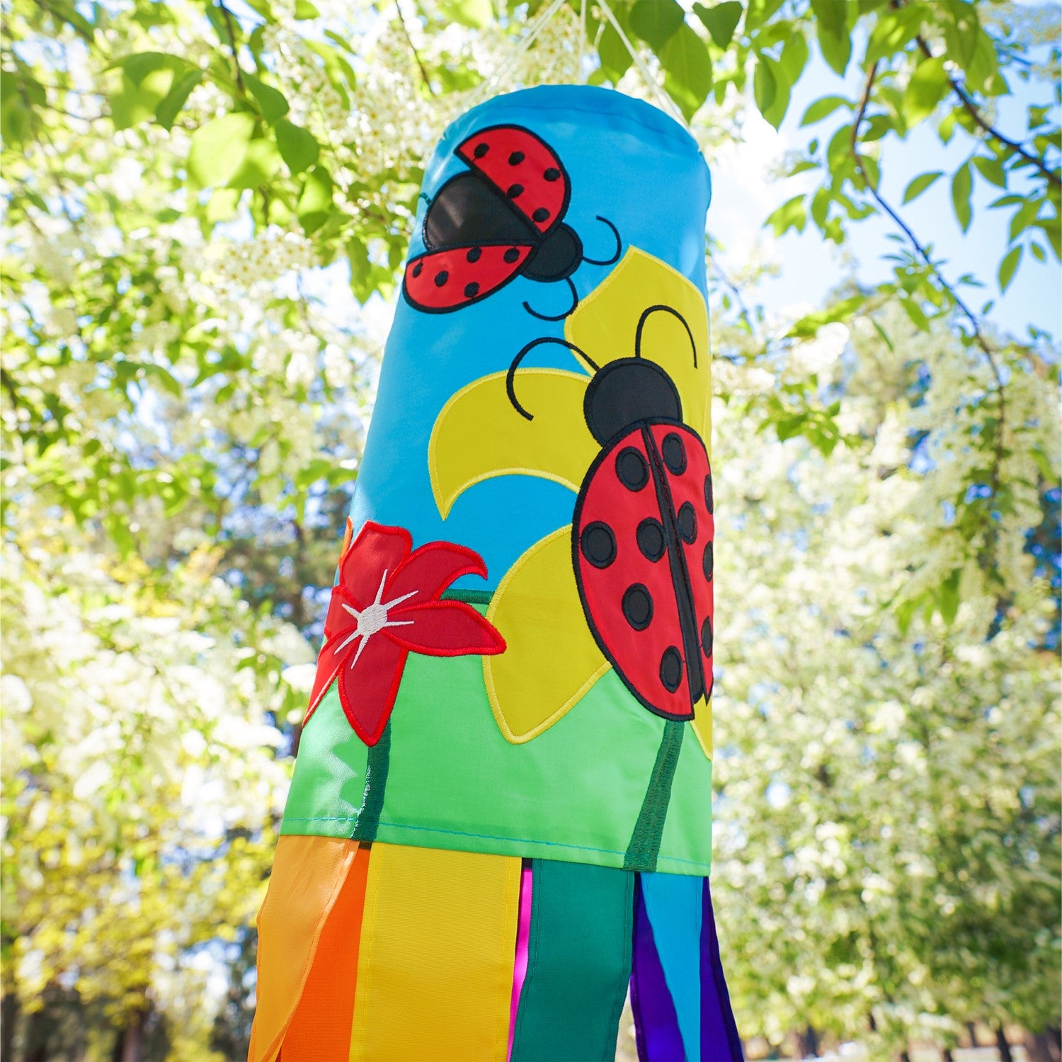A stunning Ladybug Flower 40" windsock featuring vibrant colors and detailed appliqued graphics, fluttering gracefully with eight coordinating tails.