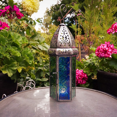 Large Blue & Green Hex Glass Tealight Lantern featuring stamped glass panels and metal frame, hanging gracefully in an outdoor setting.