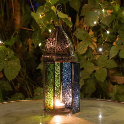 Large Blue & Green Hex Glass Tealight Lantern featuring stamped glass panels and metal frame, hanging gracefully in an outdoor setting.