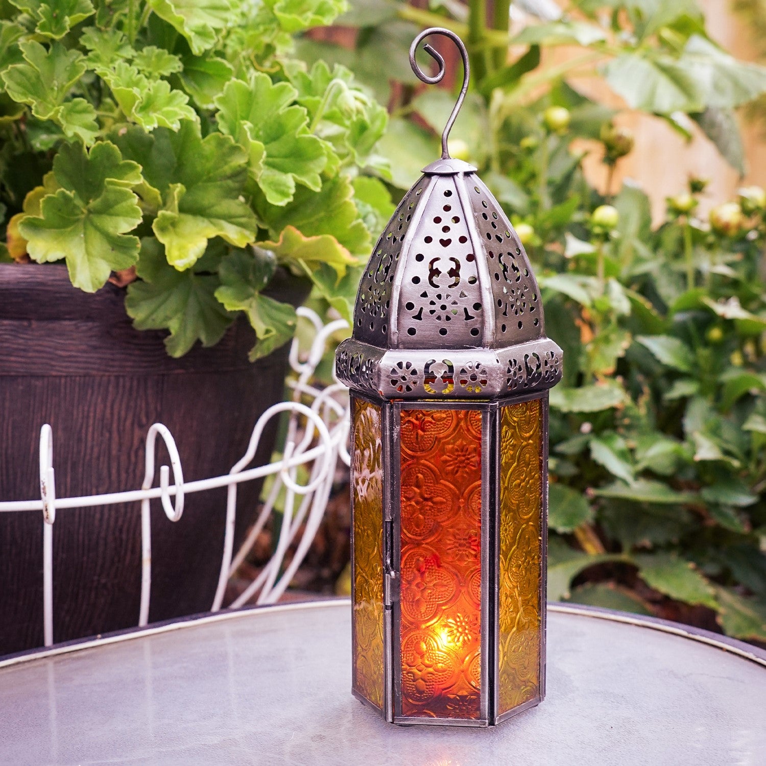 Large Orange & Yellow Hex Glass Tealight Lantern with stamped glass panels and metal accents hanging in an outdoor garden setting.