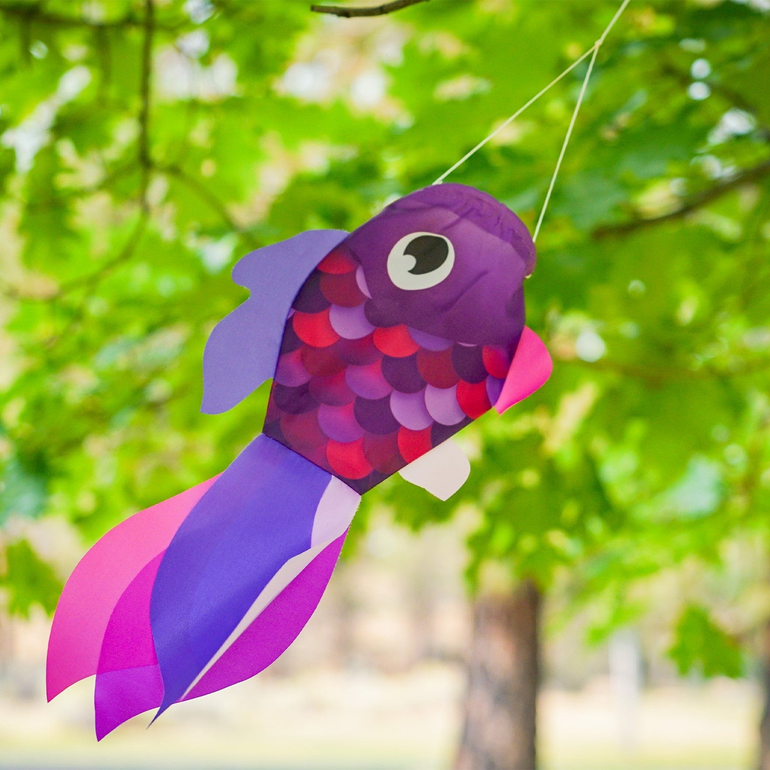 15-inch Lavender Damsel Fish windsock displaying colorful fins fluttering in the breeze against a garden backdrop.