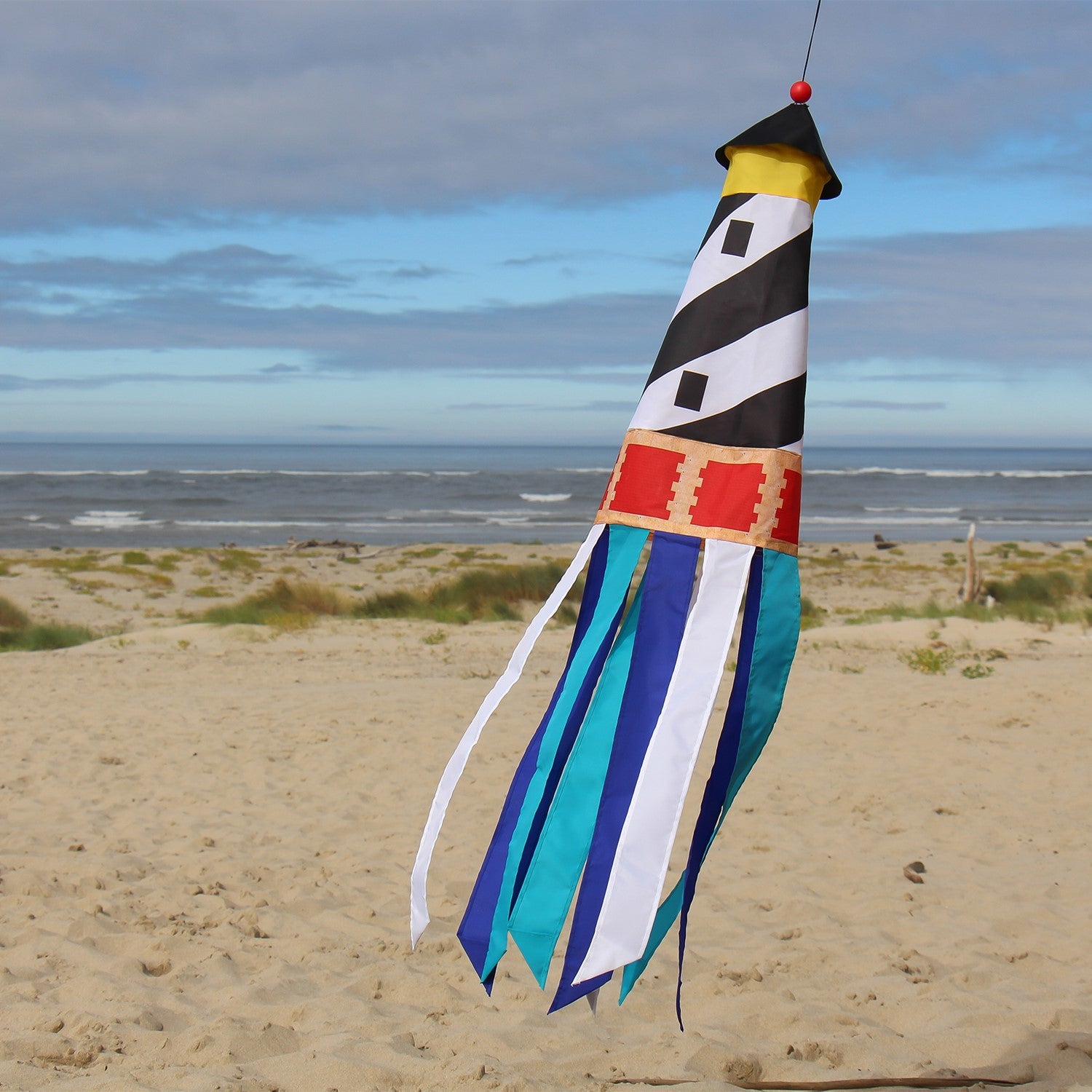 Lighthouse 3D Windsock featuring a colorful lighthouse design with fluttering tails, hanging outdoors in a breezy garden setting.