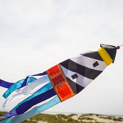 Lighthouse 3D Windsock featuring a colorful lighthouse design with fluttering tails, hanging outdoors in a breezy garden setting.