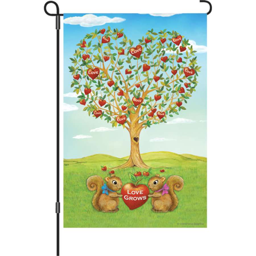 12 in. Love Grows double-sided garden flag featuring vibrant colors and soft fabric displayed in a garden setting on a sunny day.