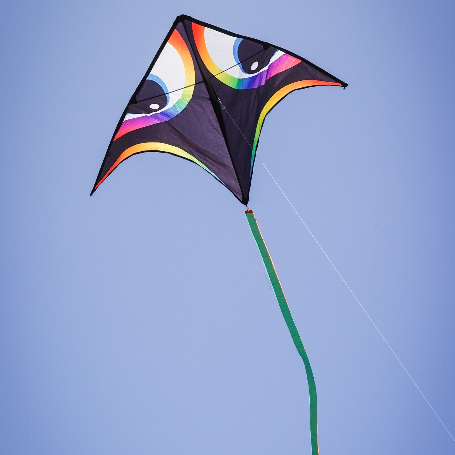 Manu Aurora 72 inch Delta Kite with vibrant colors and a streamer tail flying in a clear blue sky during a sunny day.