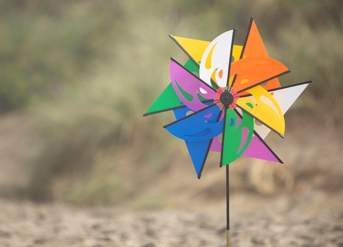 Mardi Gras Ground Spinner with colorful butterfly windsail, positioned in a garden setting, spinning gently in the breeze.