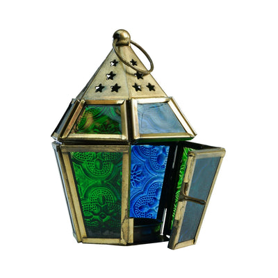 Mini Blue & Green Hex Glass Tealight Lantern with textured glass and brass accents hanging in an outdoor setting, radiating warm candlelight.