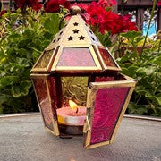 Mini Pink & Yellow Hex Glass Tealight Lantern featuring colorful stamped glass panels and a brass metal frame, displayed on a table illuminated by a candle.
